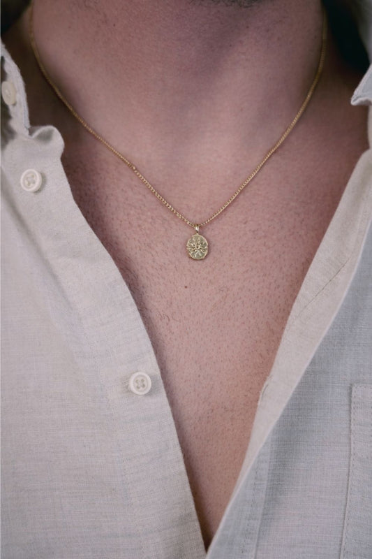 EXCITÀRE Eclipse Necklace gold with oval floral pendant, styled with open beige shirt.