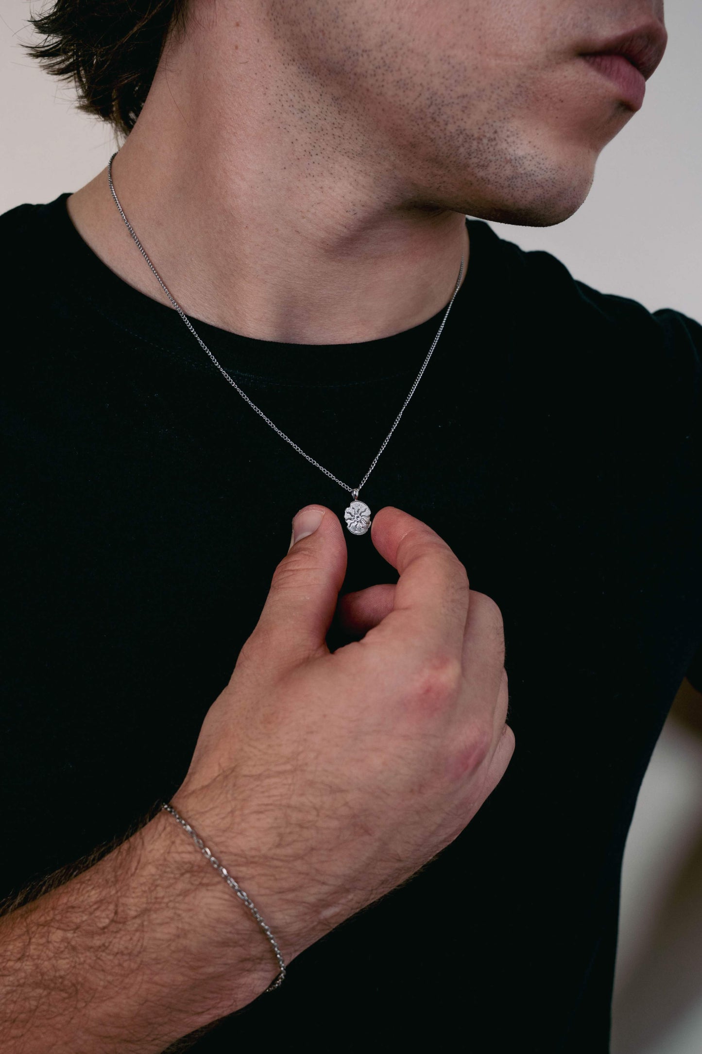 EXCITÀRE Eclipse Necklace silver with oval floral pendant, styled with black T-shirt and silver bracelet.