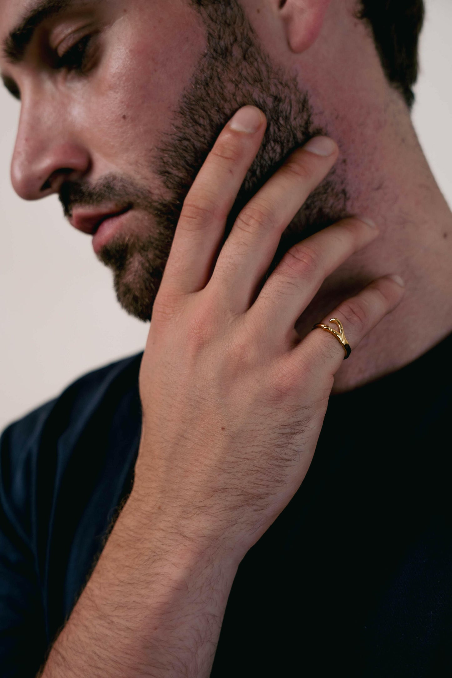 EXCITÀRE Ellis Ring gold, worn on the ring finger, hand resting on jawline in a thoughtful pose.
