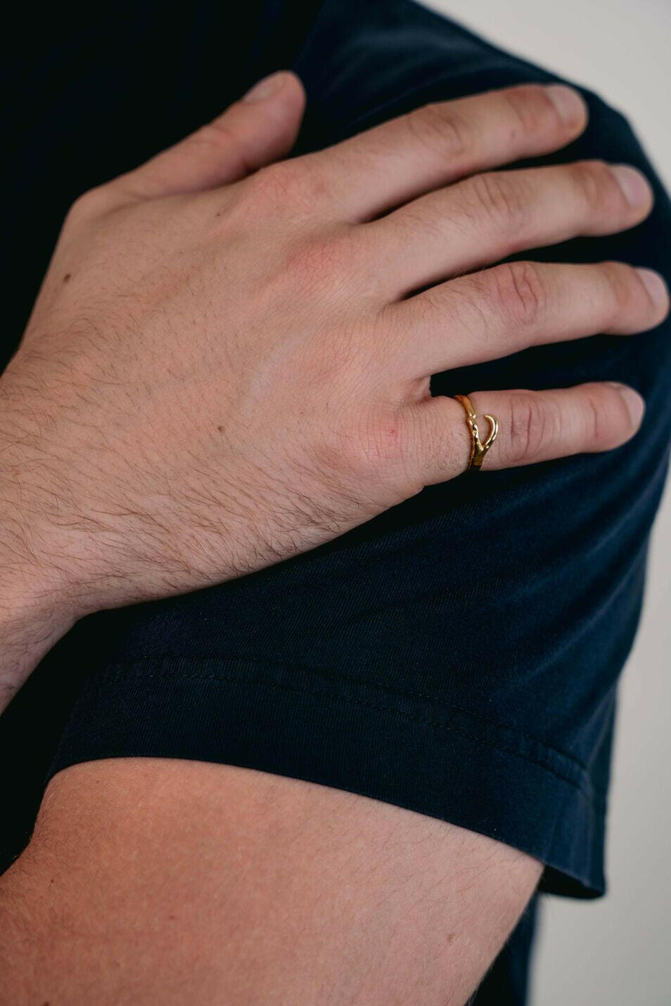 EXCITÀRE Ellis Ring gold, worn on the ring finger, hand resting on the opposite shoulder in a calm pose.