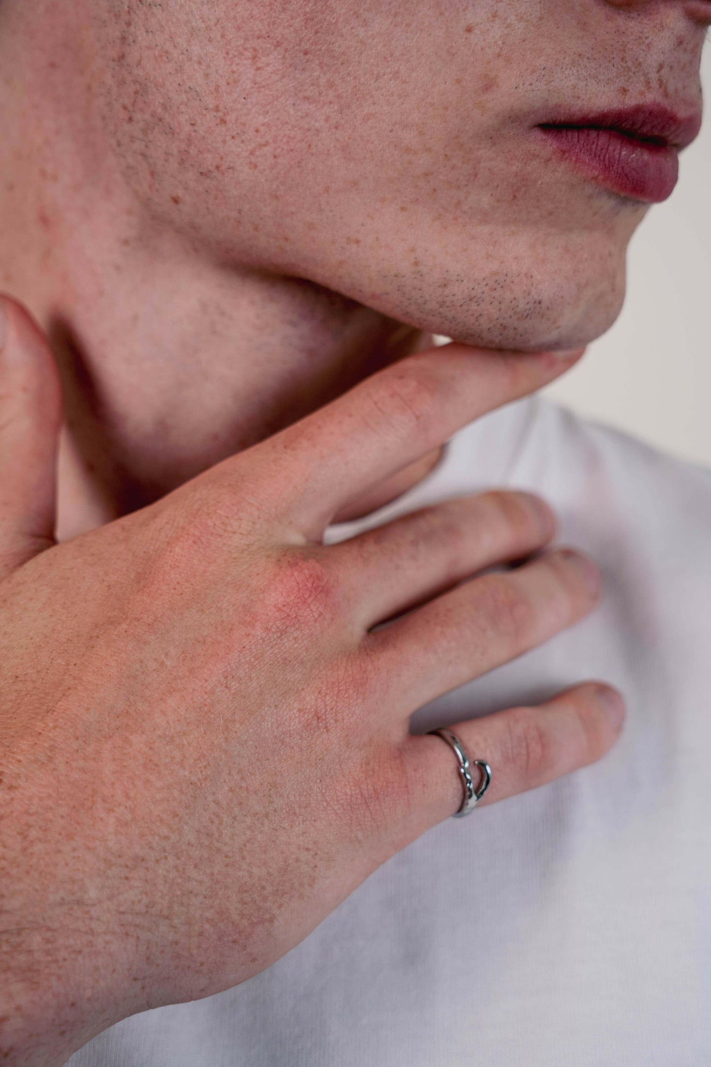 EXCITÀRE Ellis Ring silver worn on index finger, hand resting on chin, close-up portrait shot.
