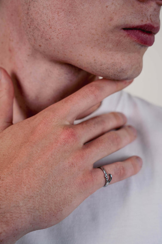 EXCITÀRE Ellis Ring silver worn on index finger, hand resting on chin, close-up portrait shot.