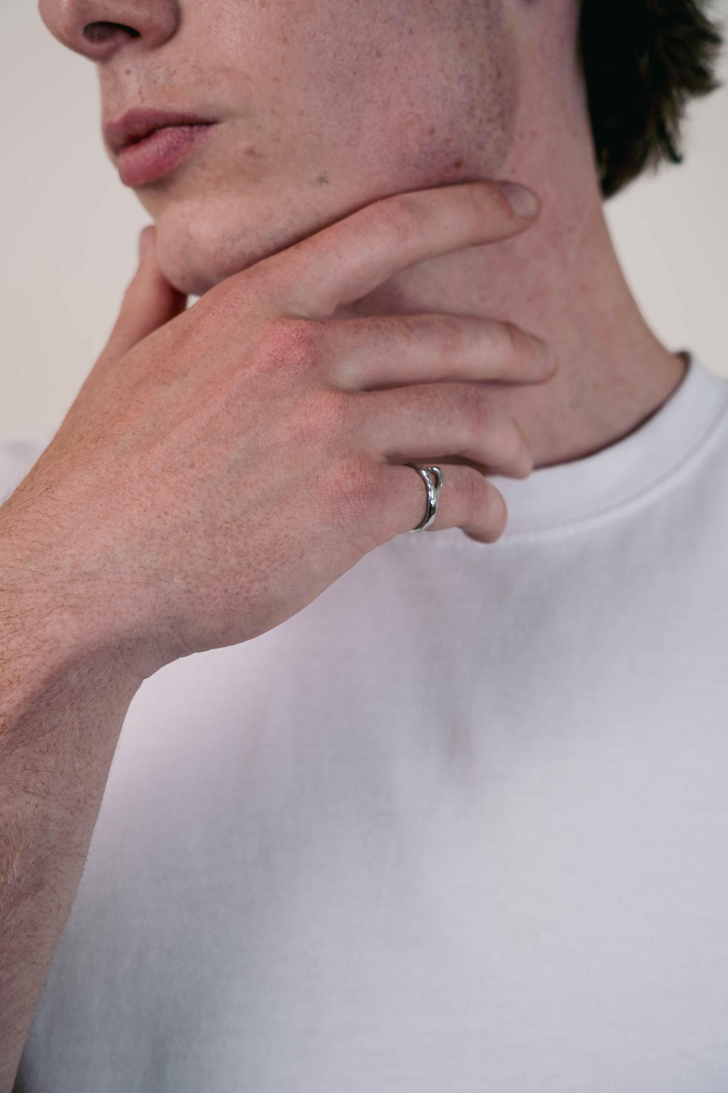 EXCITÀRE Ellis Ring silver shown on index finger, hand placed under chin, model in white T-shirt.
