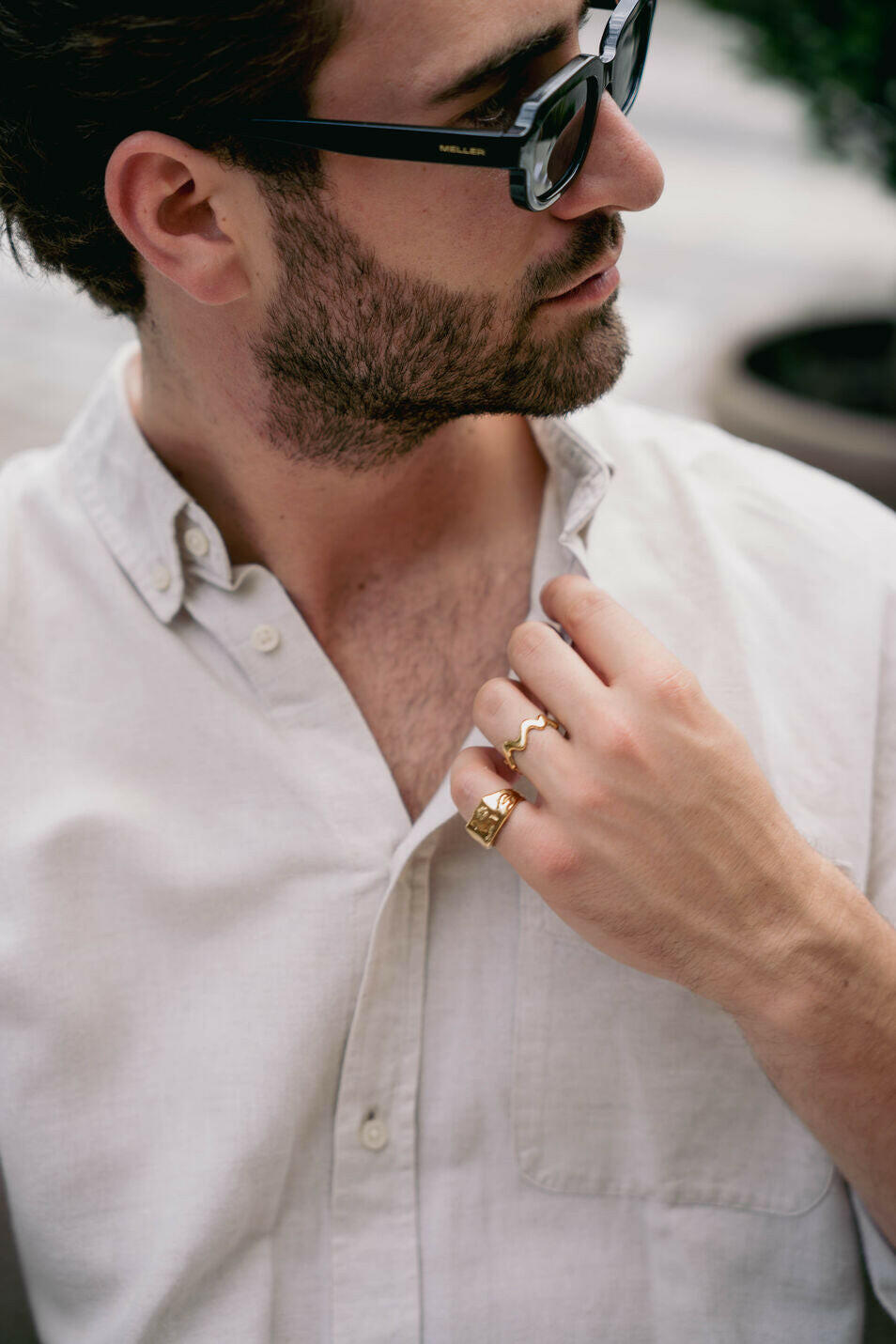 EXCITÀRE Ember Ring gold stacked with Flower Ring gold, worn with light shirt and sunglasses outdoors.