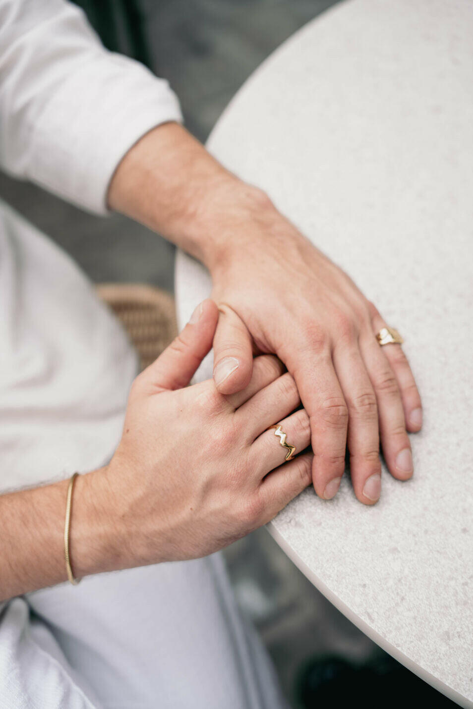 EXCITÀRE Ember Ring gold on hand, styled with matching gold bracelet, shot at a round terrazzo table.