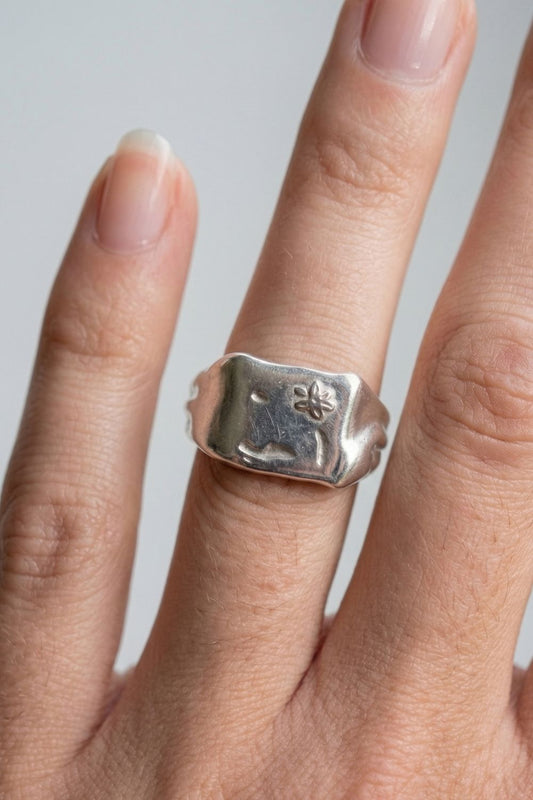 Silver Flower Signet ring with a floral design on a Female finger against a neutral background
