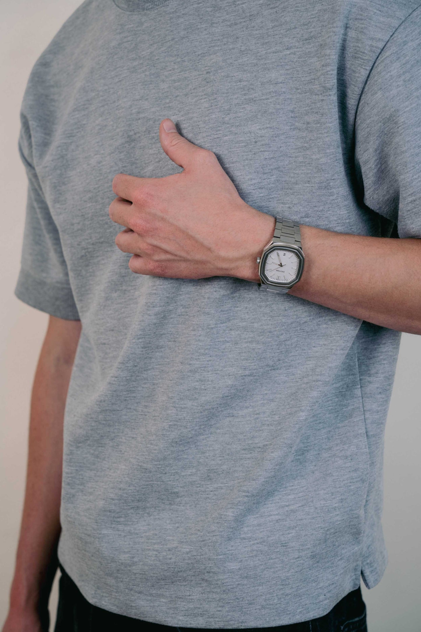 Close-up of a man wearing the Lumen White Watch with a brushed silver strap, arm relaxed at his side in casual outfit.