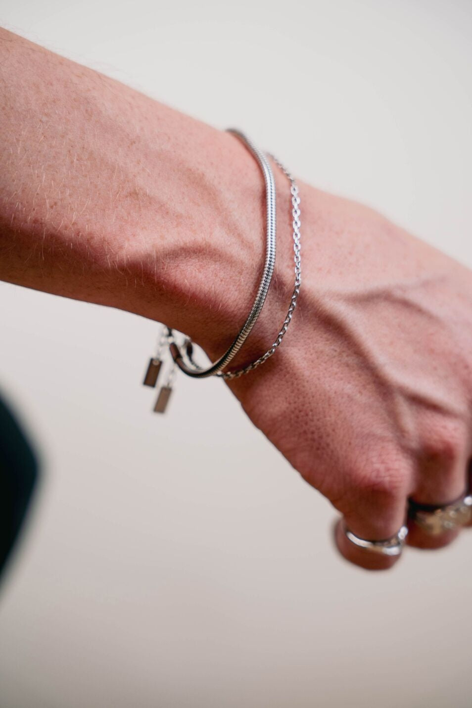 EXCITÀRE Nova Bracelet silver, worn on wrist next to Figaro bracelet, shown in close-up detail.