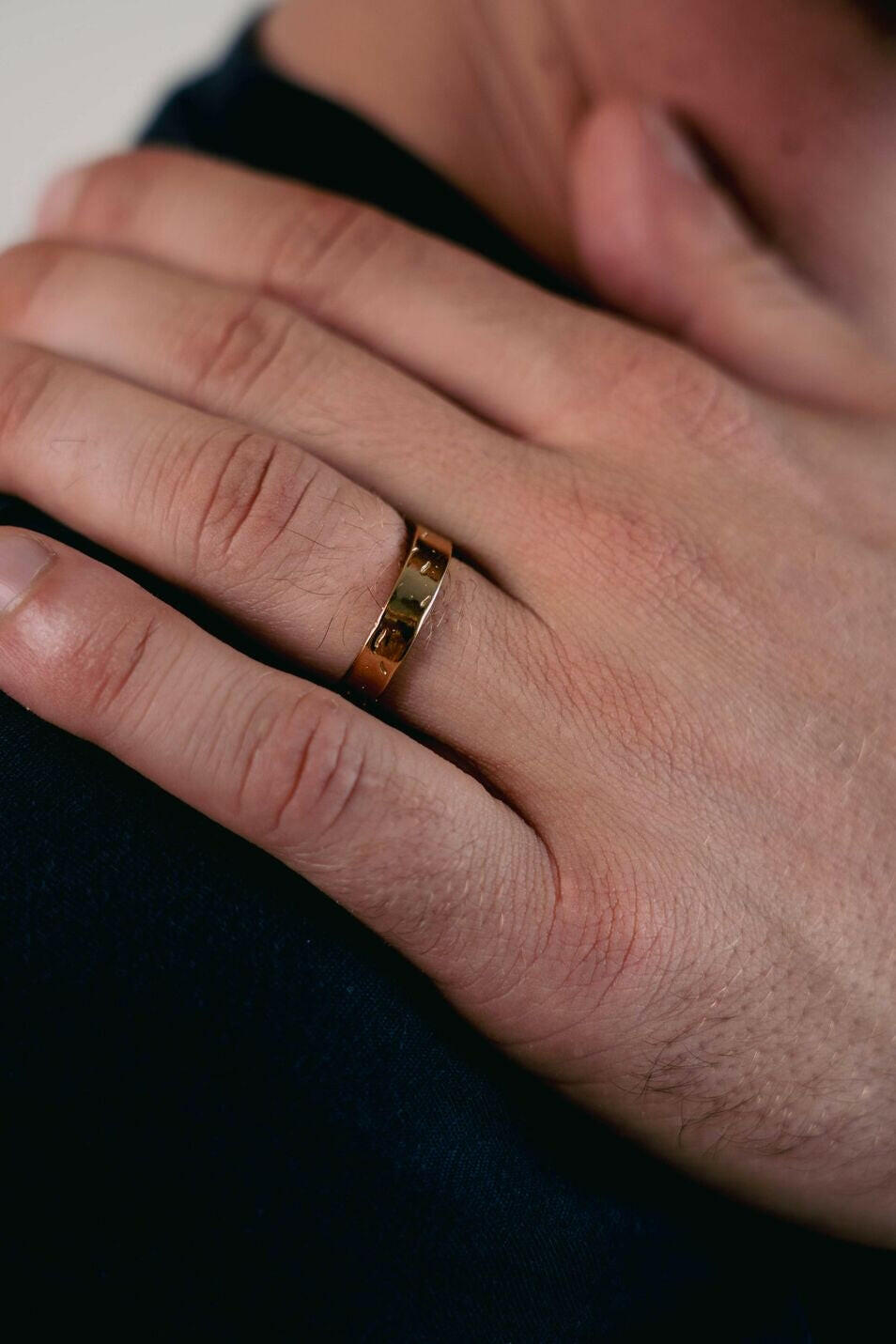 EXCITÀRE Brand Ring gold, worn on right hand, hand resting on shoulder in a relaxed pose.