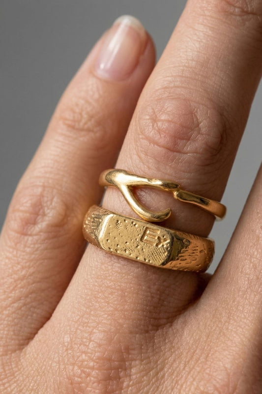 
  Close-up of a female hand wearing two gold rings on a neutral background
