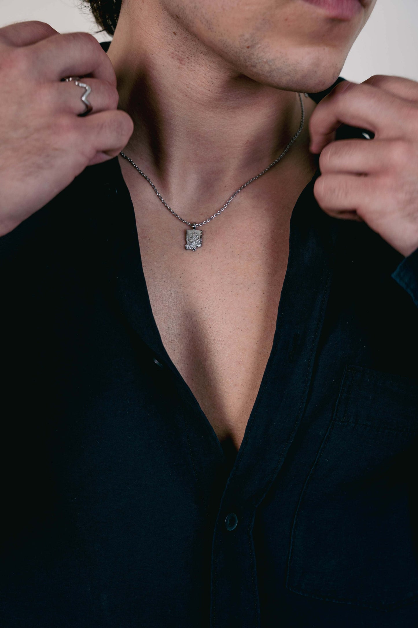 EXCITÀRE Flower Necklace silver with floral pendant, styled with open black shirt and silver ring.