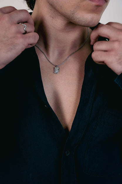 EXCITÀRE Flower Necklace silver with floral pendant, styled with open black shirt and silver ring.