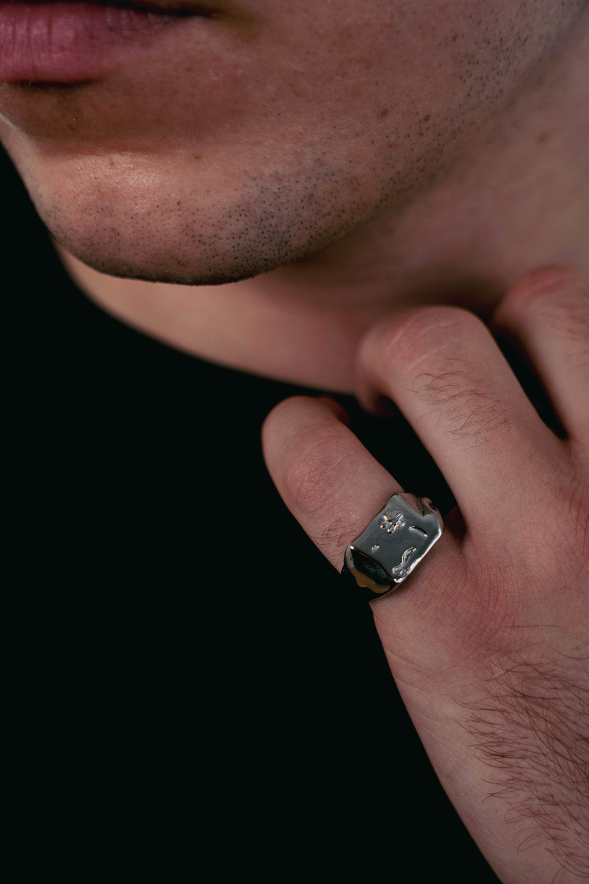 Close-up of the EXCITÀRE Flower Ring in silver with engraved floral detail, worn on the hand against a dark t-shirt.