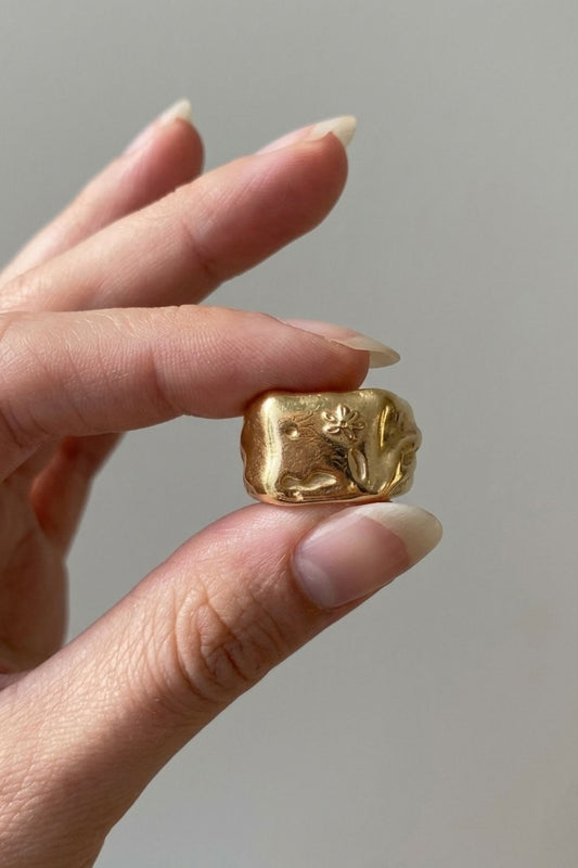 
  Gold Flower Ring being worn on a Female finger against a neutral background
