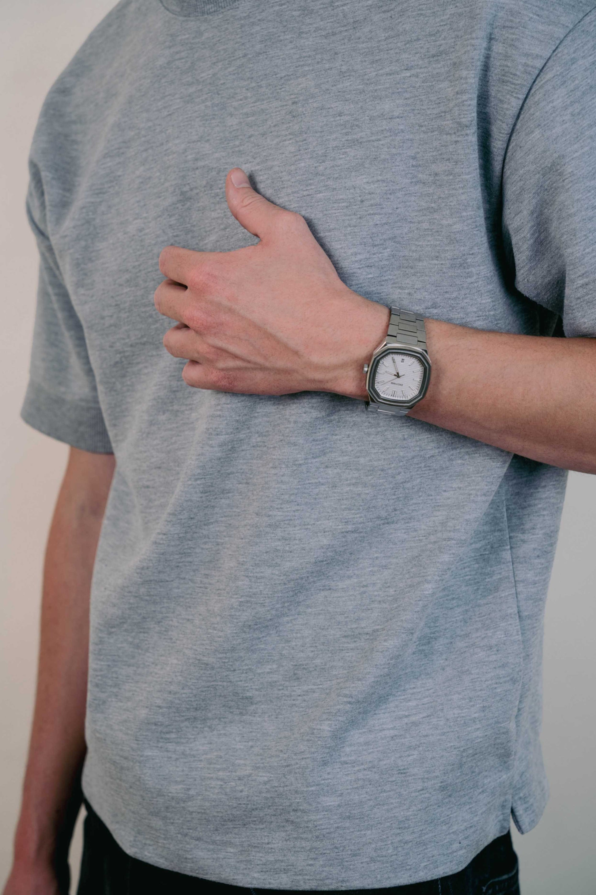 Close-up of a man wearing the Lumen White Watch with a brushed silver strap, arm relaxed at his side in casual outfit.