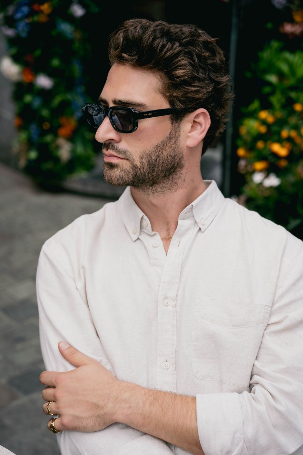 EXCITÀRE Nova Necklace gold, worn around the neck, paired with sunglasses and an open cream shirt, seated pose with head turned sideways.