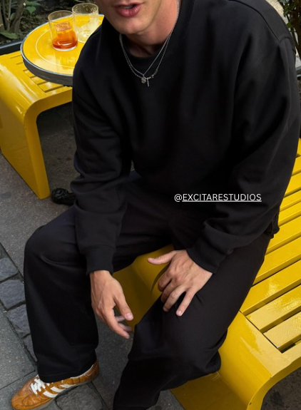 Customer wearing EXCITÀRE Eclipse Necklace and Nova Chain layered over a black sweatshirt. Minimal silver jewelry styled with casual streetwear.
