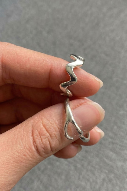 Silver Ellis and Ember Ring held between fingers against a neutral background