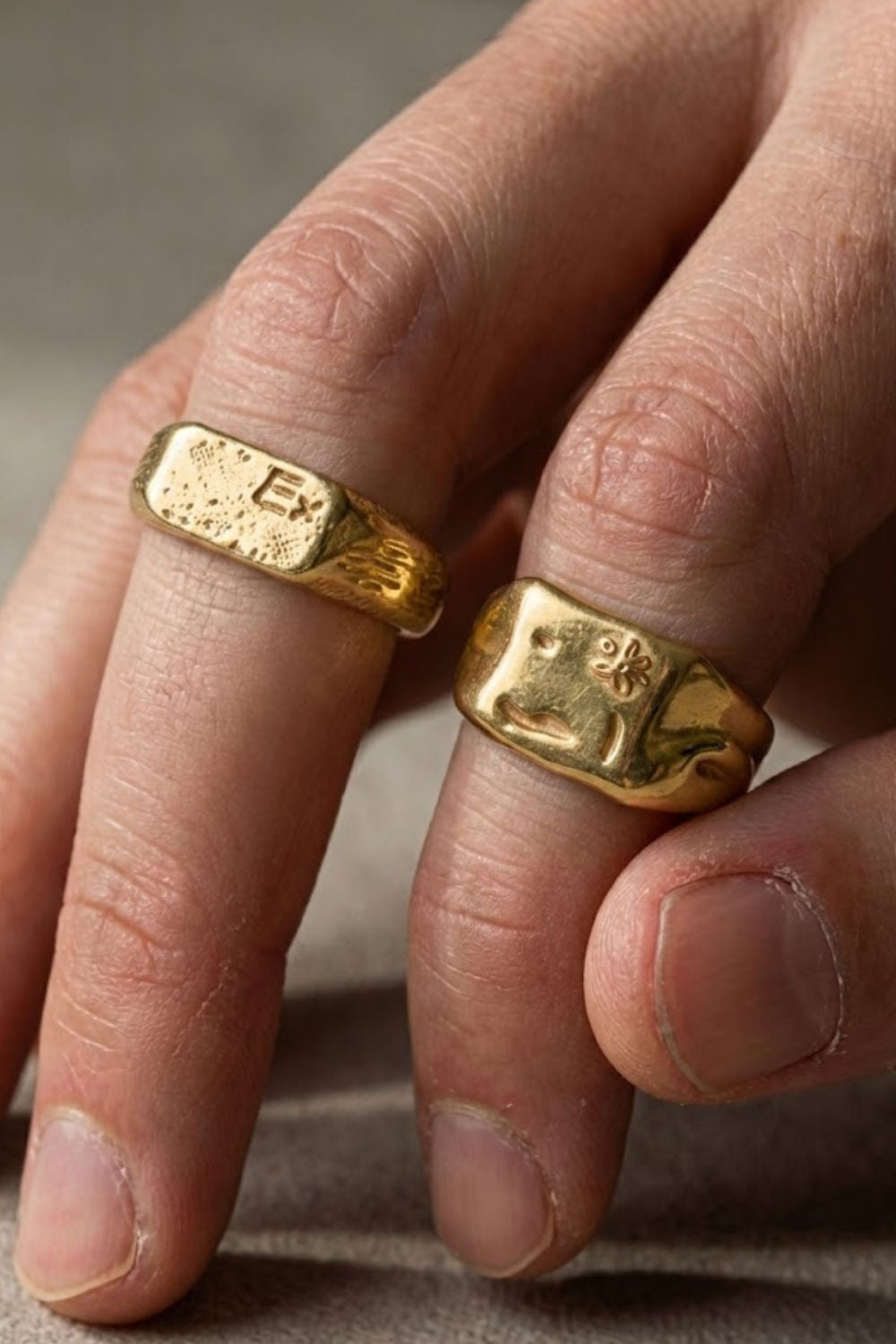 Close-up of the Excitare Ring Gold Extra ring stack, featuring two bold minimalist gold rings with engraved EXCITARE and flower details, worn on the hand.