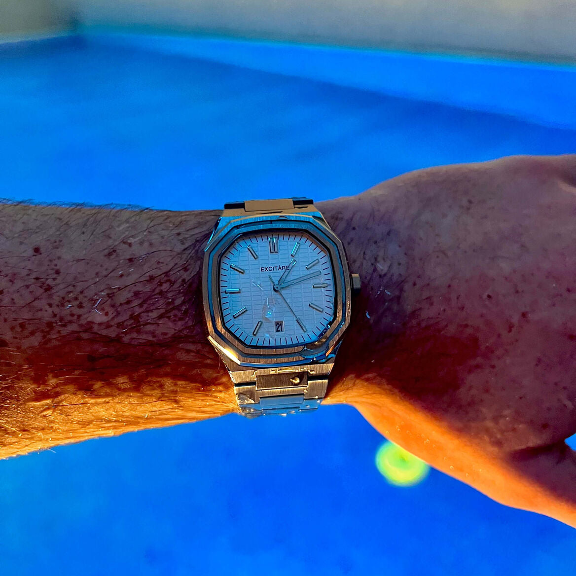 EXCITÀRE Lumen White Watch in stainless steel worn near a pool, showcasing water resistance