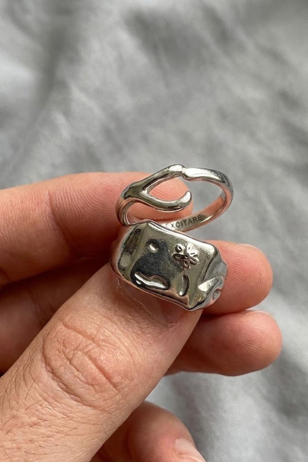 Close-up of the Flower Ring Extra ring stack in silver, featuring a bold signet ring with engraved flower detail paired with a minimalist open ring.