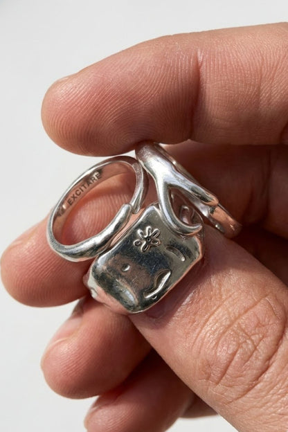 Close-up of the Flower Ring Stack Extra in silver, showing layered minimalist rings with engraved flower details, worn together on the hand.
