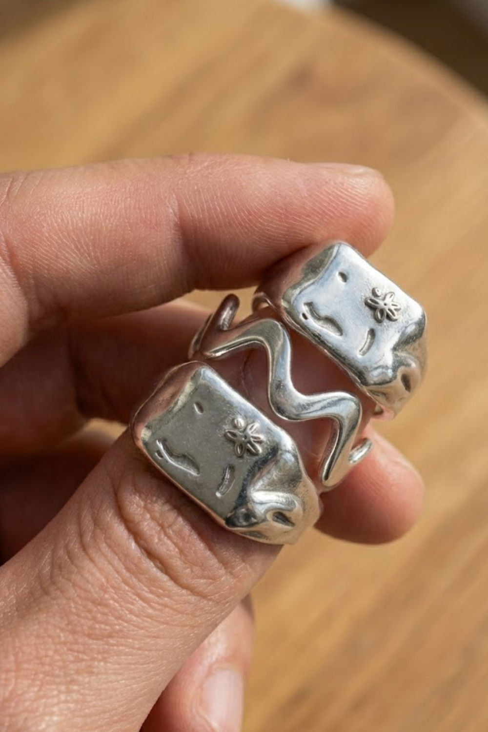 Top view of the Wave Ring Extra ring stack in silver, featuring two bold signet rings with engraved flower details paired with a wave-shaped ring.