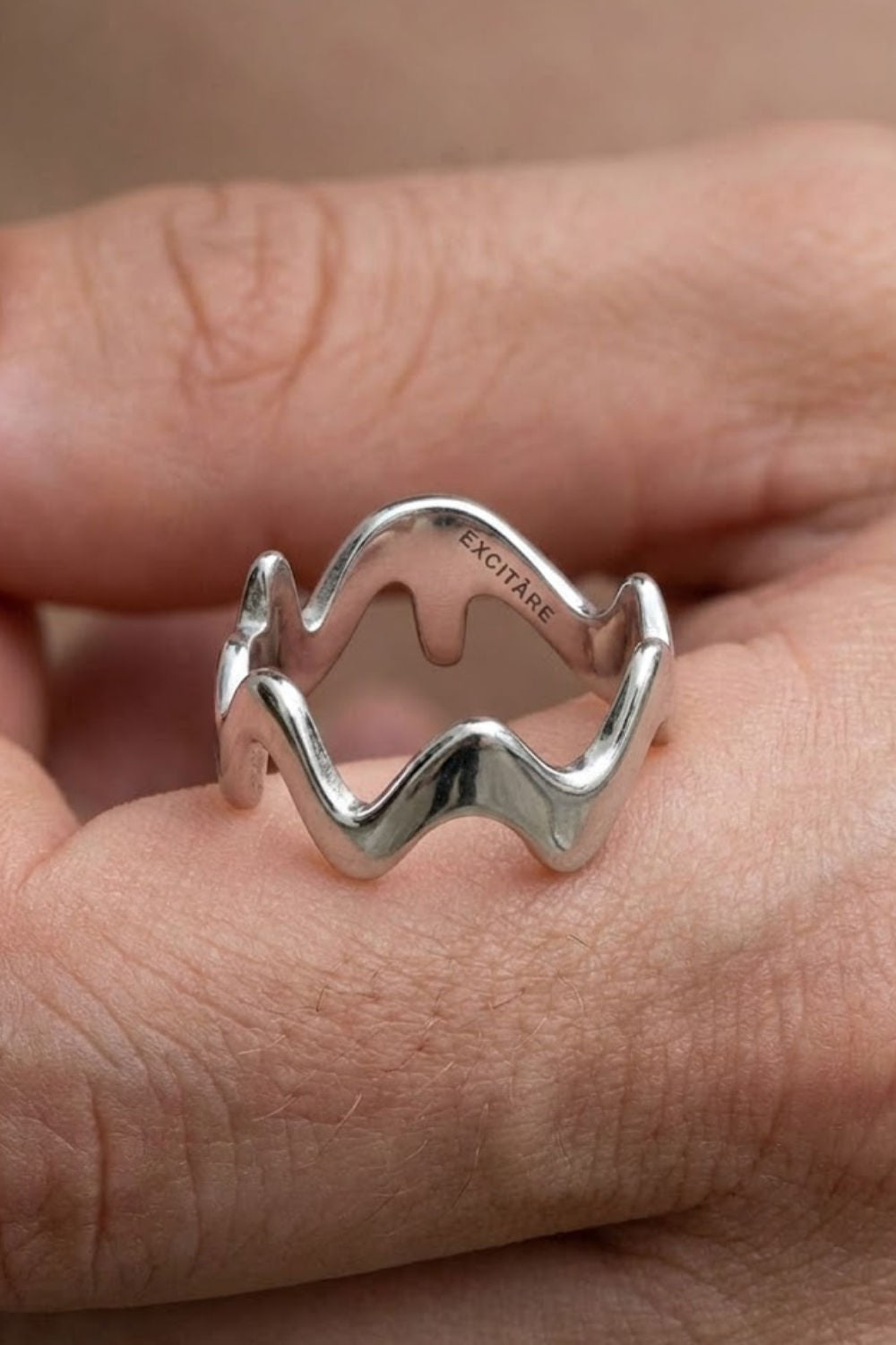 Top view of the Wave Ring Extra in silver, featuring a flowing minimalist wave design with engraved EXCITARE branding.